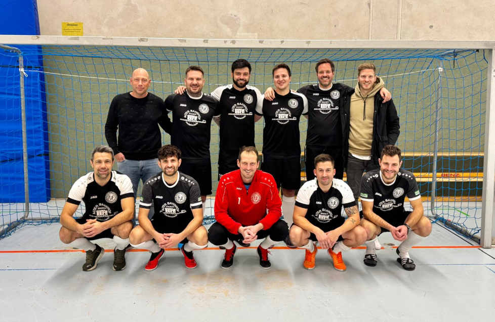 Eine Gruppe von lächelnden Männern, die gemeinsam vor einem Sportnetz posieren und einen Moment der Kameradschaft festhalten.