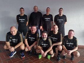 Eine Gruppe von Männern in schwarzen Hemden steht zusammen und lächelt für ein Foto.