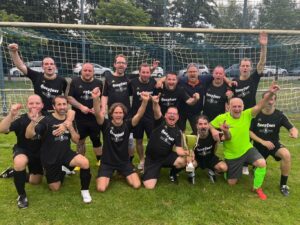 Eine Gruppe von lächelnden Männern, die gemeinsam vor einem Fußballtor posieren und Kameradschaft und Teamgeist demonstrieren.