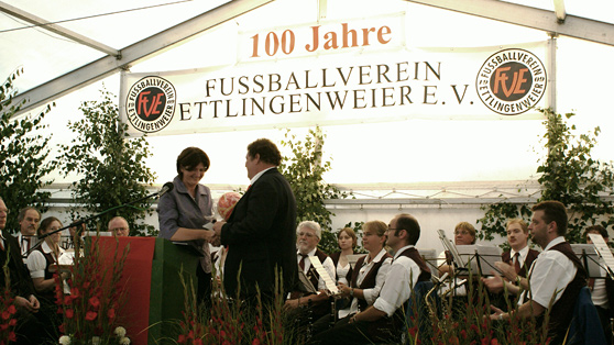 Mehrere Personen versammeln sich vor einem Zelt und genießen die gemeinsame Zeit im Freien