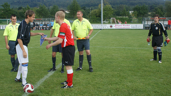 Eine Gruppe von Männern steht auf einem Fußballfeld und beobachtet das Spiel