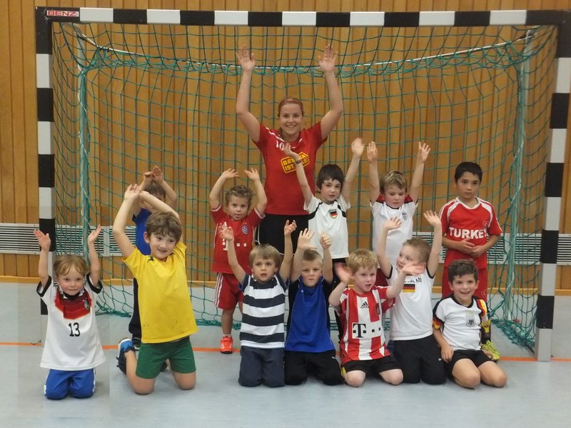 Kinder stehen lächelnd vor einem Fußballtor und posieren für ein Gruppenfoto.