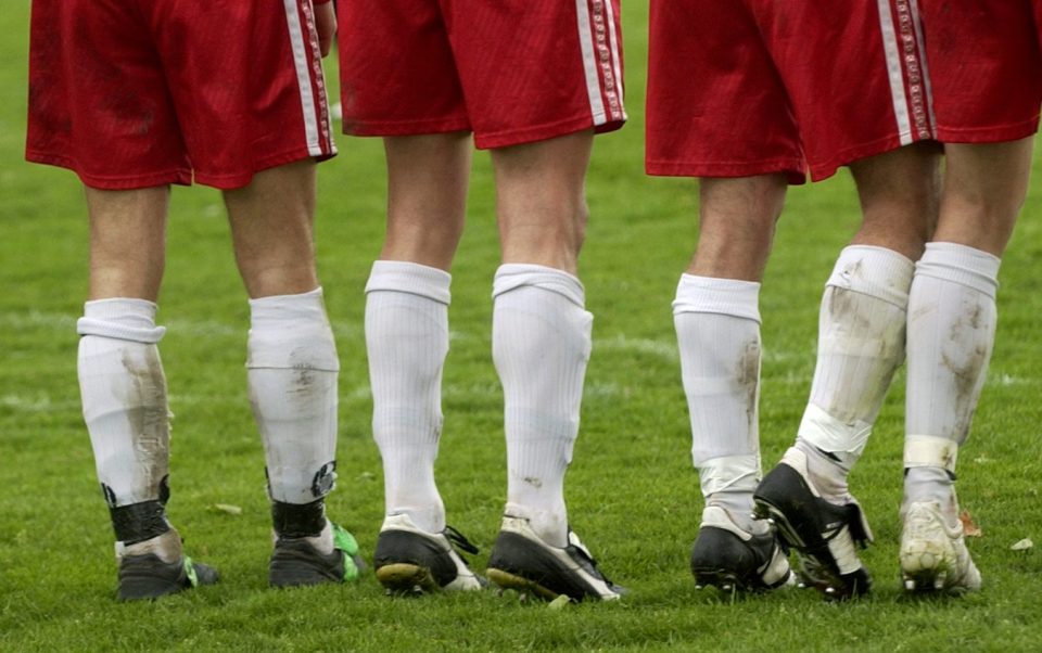 Fußballspieler in roten und weißen Trikots stehen auf dem Spielfeld und bereiten sich auf das Spiel vor.