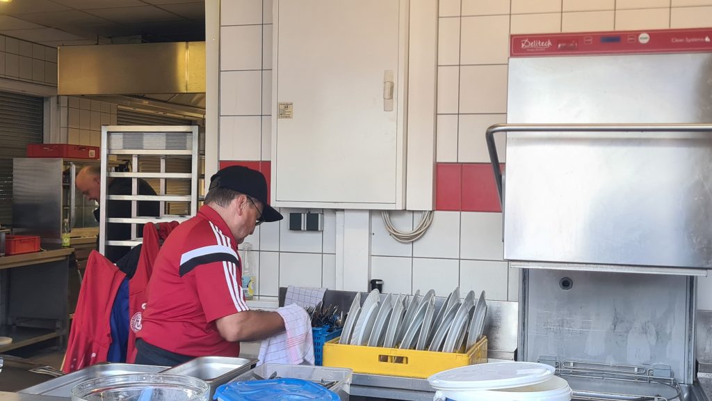 Ein Mann steht an der Spülmaschine und trocknet einen Teller ab