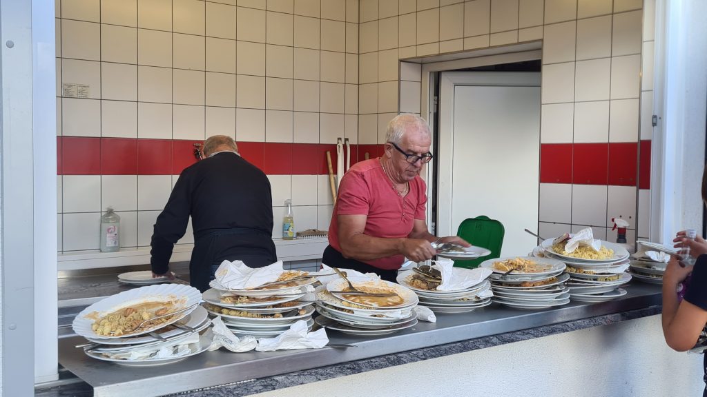 Spüldienst in der Küche mit vielen ungespülten Tellern im Vordergrund