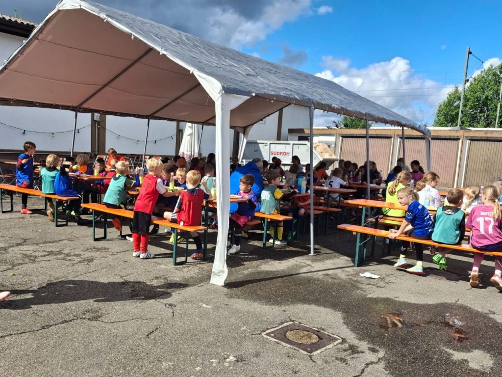 Sehr viele Kinder im Zelt und daneben auf Bierbänken beim Mittagessen