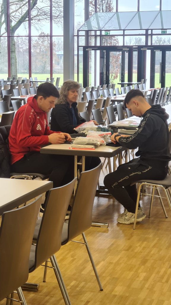 2 Spieler und 1 Frau wickeln das Besteck in Servietten